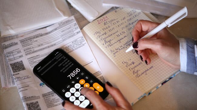 Девушка подсчитывает коммунальные платежи у себя дома в Киеве